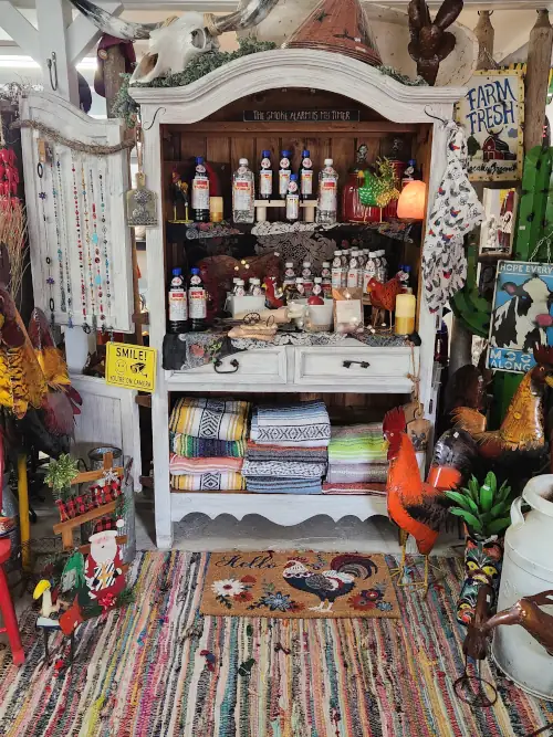 Rustic wooden hutch displaying hand-painted Mexican pottery, decorative plates, and bottles of pure vanilla at Cantaimer Shopping in Hico, Texas